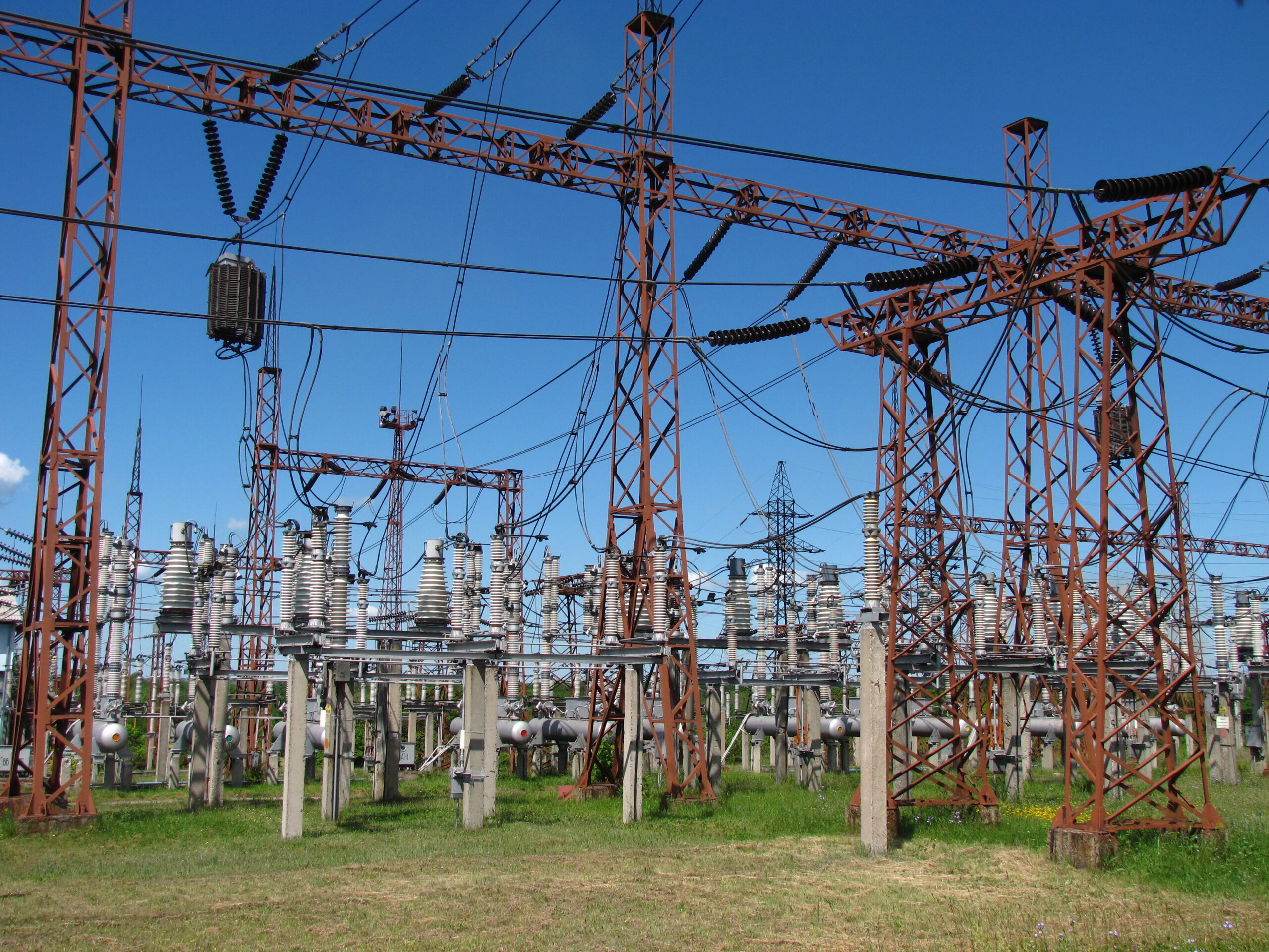 Ground-level view of high-voltage substation switchgear showing insulators and conductor wiring