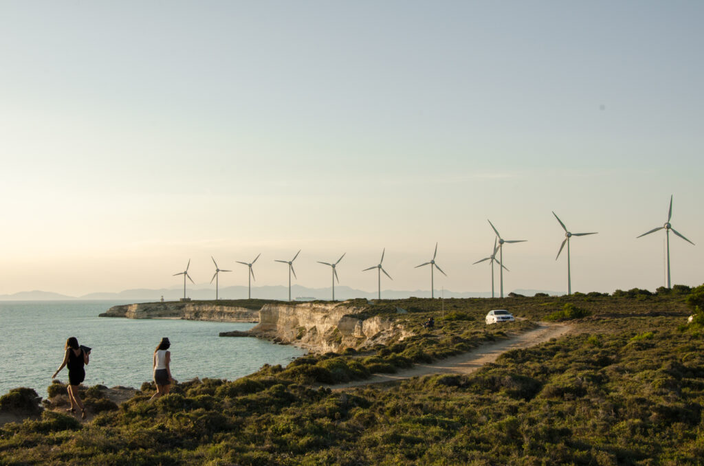 Row of wind turbines along a coastal cliff at sunset